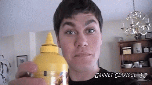 A Man Is Holding A Bottle Of Garret Claridge 10 Mustard GIF