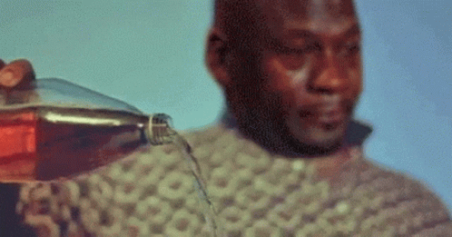 A Man Is Holding A Bottle Of Soda And Pouring It On His Face . GIF