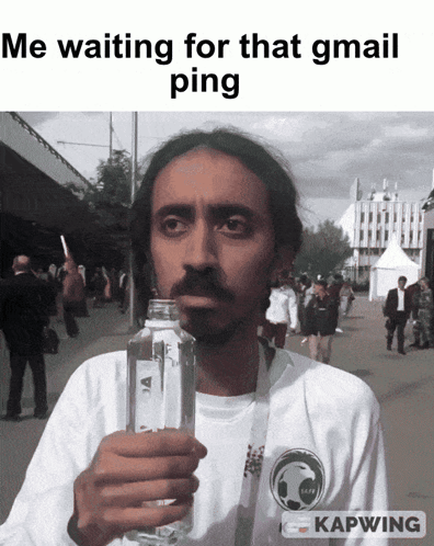A Man Is Holding A Bottle Of Water In Front Of A Sign That Says Kapwing GIF