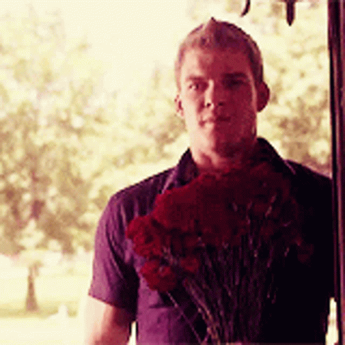 A Man Is Holding A Bouquet Of Red Flowers GIF