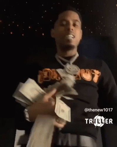 A Man Is Holding A Bunch Of Money In His Hands In A Dark Room . GIF