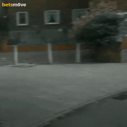 A Man Is Holding A Camera In Front Of A Building With The Words Betsmove On The Bottom GIF
