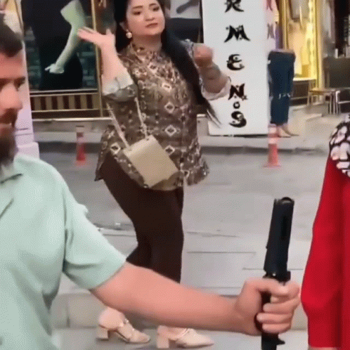 a man is holding a camera while a woman stands in front of a sign that says ' n ' on it