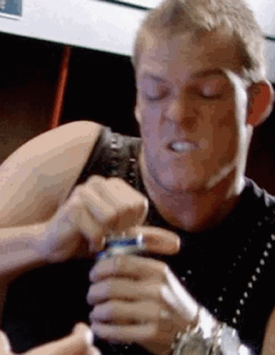 A Man Is Holding A Can Of Soda In His Hand And Making A Face . GIF