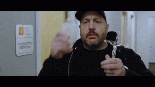 A Man Is Holding A Cross In Front Of A Handicapped Restroom Sign GIF