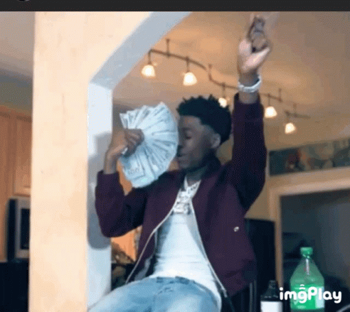 A Man Is Holding A Fan Of Money In His Hand . GIF