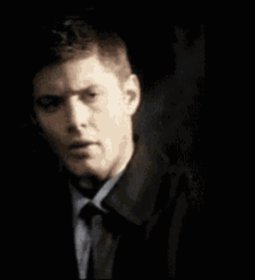 A Man Is Holding A Fbi Badge In Front Of His Face . GIF
