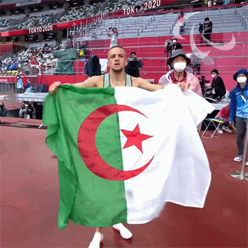 A Man Is Holding A Flag That Says Tokyo 2020 On It GIF