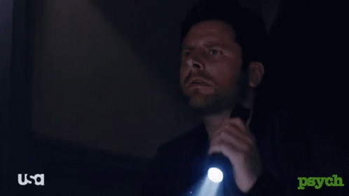 A Man Is Holding A Flashlight In A Dark Room With A Usa Logo In The Corner GIF