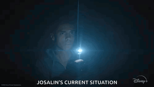 A Man Is Holding A Flashlight In The Dark And Looking At It . GIF