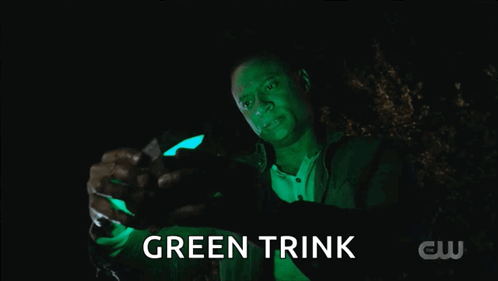 A Man Is Holding A Green Object That Says Green Trink On It GIF