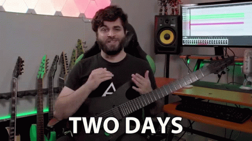 A Man Is Holding A Guitar In Front Of A Computer And Says " Two Days " GIF