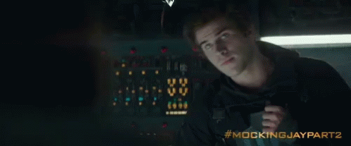 A Man Is Holding A Gun In A Dark Room With The Words Mockingjay Part 2 Written On The Bottom GIF