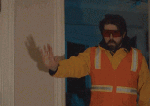 A Man Is Holding A Gun In Front Of A Door That Says Focus GIF