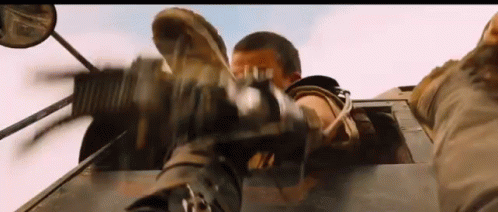 A Man Is Holding A Gun In His Hand While Driving A Car . GIF
