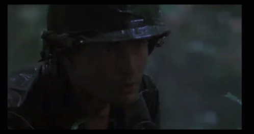 A Man Is Holding A Gun In The Woods . GIF