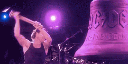 A Man Is Holding A Hammer In Front Of A Large Bell That Says Ac Dc On It GIF