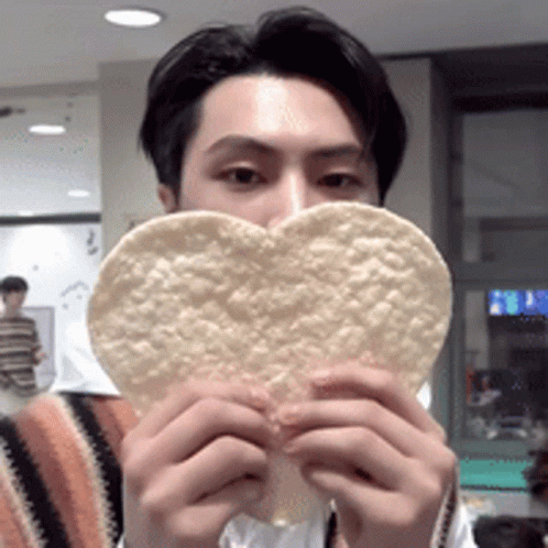 A Man Is Holding A Heart Shaped Tortilla Chip GIF