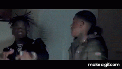A Man Is Holding A Knife In His Hand While Another Man Is Standing Next To Him . GIF