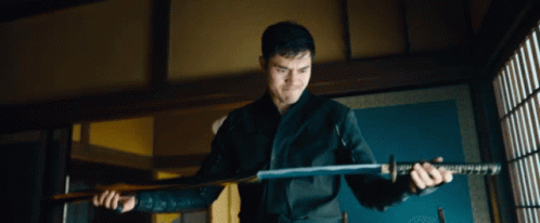 A Man Is Holding A Large Sword In His Hands GIF