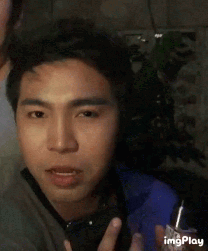 A Man Is Holding A Lighter In His Hand And Making A Face . GIF