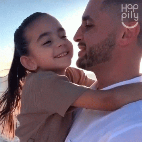 A Man Is Holding A Little Girl In His Arms With The Word Hap Pillu On The Bottom Right GIF