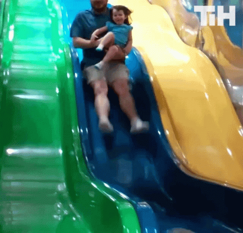 A Man Is Holding A Little Girl On A Slide And The Letters Th Are On The Bottom Of The Slide GIF