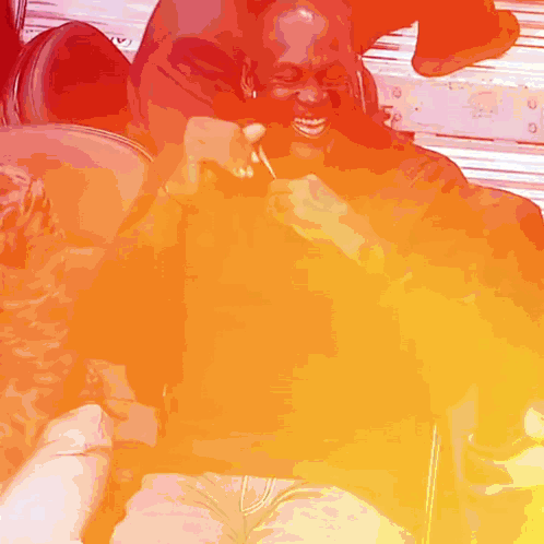 A Man Is Holding A Lollipop And Smiling While Sitting On A Chair GIF