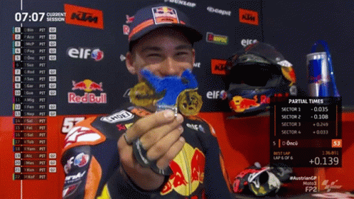 A Man Is Holding A Medal In Front Of A Red Bull Sign GIF