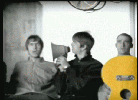 a man is holding a megaphone while standing next to two other men .