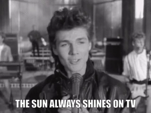 A Man Is Holding A Microphone And Singing Into It In A Black And White Photo . GIF