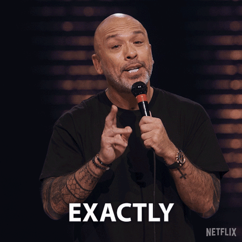 A Man Is Holding A Microphone And The Word Exactly Is Above Him GIF
