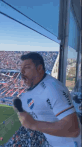 a man is holding a microphone in front of a crowd at a soccer game ..