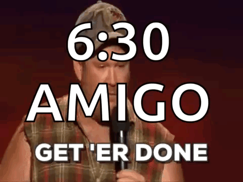 A Man Is Holding A Microphone In Front Of A Sign That Says Amigo Get ' Er Done GIF