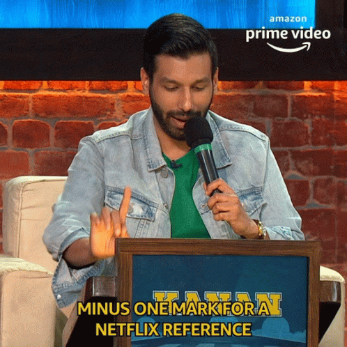 A Man Is Holding A Microphone In Front Of An Amazon Prime Video Sign GIF