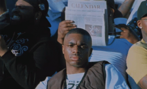 A Man Is Holding A Newspaper That Says Calendar GIF