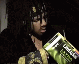 A Man Is Holding A Pack Of Lifestyles Ultra Sensitive Condoms GIF
