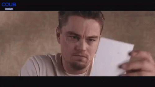 A Man Is Holding A Piece Of Paper In His Hand And Making A Face . GIF