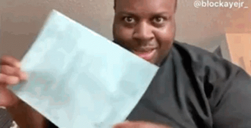 A Man Is Holding A Piece Of Paper In His Hands And Smiling At The Camera . GIF
