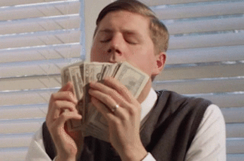 A Man Is Holding A Pile Of Money In His Mouth GIF