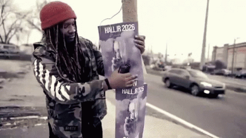 A Man Is Holding A Poster That Says Hall Jr 2026 GIF