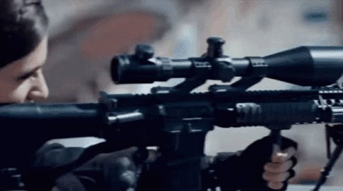 a man is holding a rifle with a sniper scope on it .
