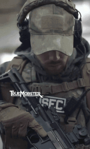 A Man Is Holding A Rifle With The Letters Sfc On His Chest GIF