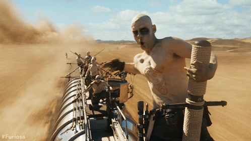A Man Is Holding A Rope In The Desert With #Furiosa On The Bottom Right GIF