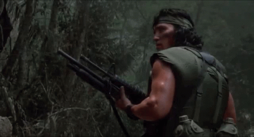 A Man Is Holding A Shotgun In The Woods GIF