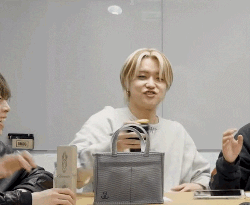 A Man Is Holding A Small Bag That Says ' Bmdg ' On It GIF