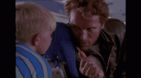 A Man Is Holding A Small Child 'S Face While Sitting On A Plane GIF