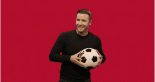 A Man Is Holding A Soccer Ball In Front Of A Sports Logo GIF
