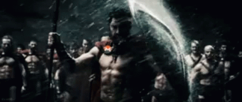 A Man Is Holding A Spear In Front Of A Group Of Spartans . GIF