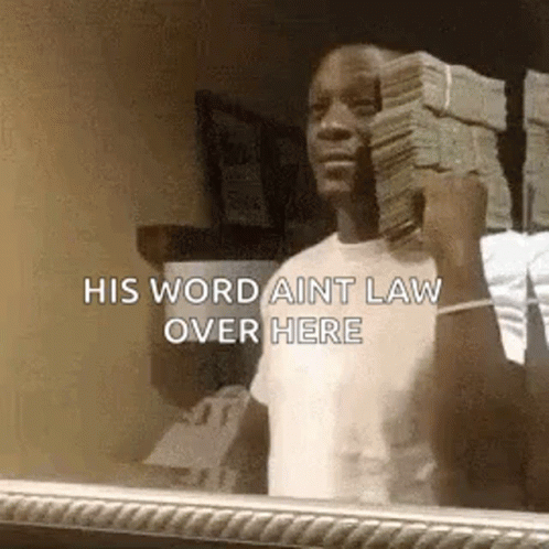 A Man Is Holding A Stack Of Money In Front Of A Mirror And Saying `` His Word Aint Law Over Here '' . GIF